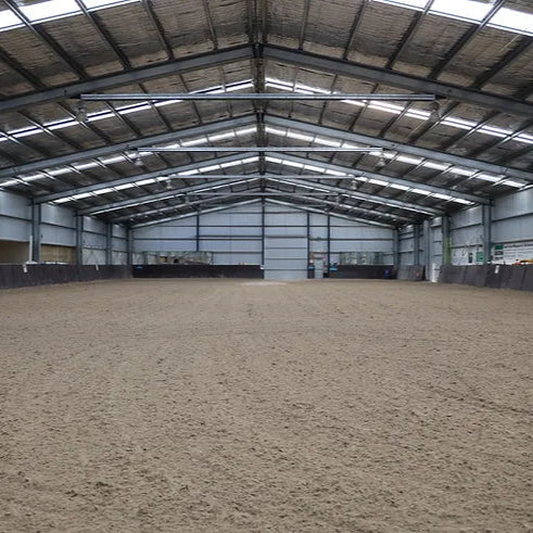 Large indoor equestrian arena with a sand silica base and lights for night riding events.
