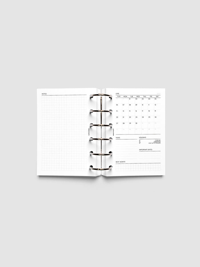 2027 Dated Monthly Admin Inserts open inside a Pocket 6-Ring Punch 6-ring planner, showing the fully open graph left page alongside the Sunday start monthly calendar, task section, holiday reference, important dates, and next month preview on the right.
