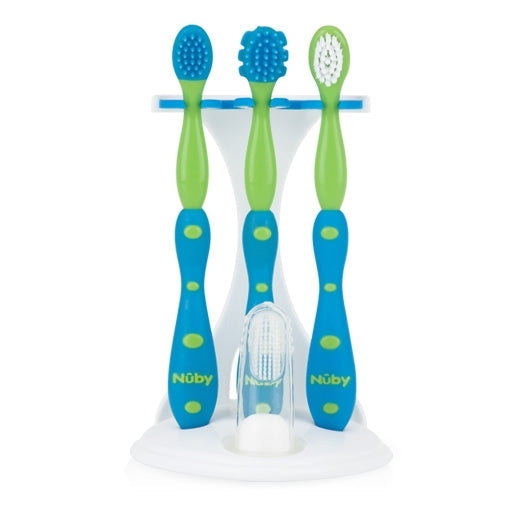 Three blue and green Nuby toothbrushes with varied brush heads stand upright on a white holder, plus a clear silicone finger brush—this is the Nuby 4-Stage Oral Care System for dental hygiene.