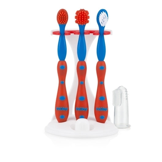 Three red and blue baby toothbrushes with different bristle styles stand upright in a white holder next to a clear silicone finger toothbrush, all part of the 4-Stage Oral Care System for dental hygiene.