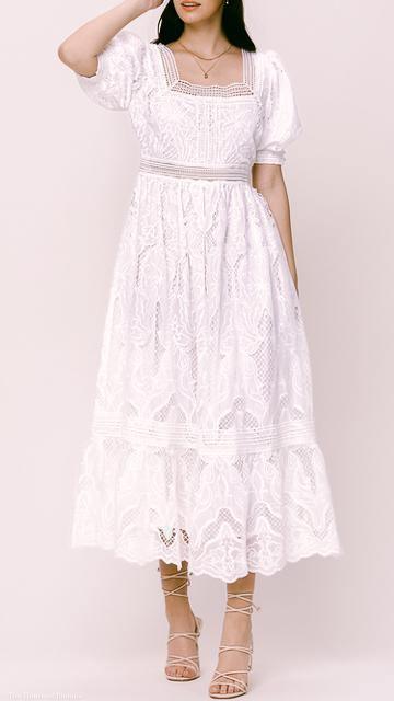 Woman wearing a white broderie anglaise puff sleeve square neck maxi dress with lace details and strappy beige heels