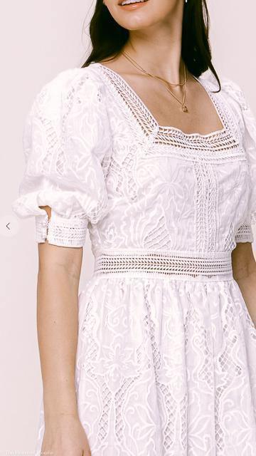 Close-up of a white broderie anglaise lace maxi dress with puff sleeves and square neckline at upscale women's boutique