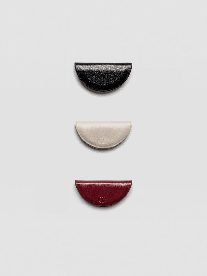 A set of three semi-circle leather magnetic bookmarks in black, cream, and burgundy colors